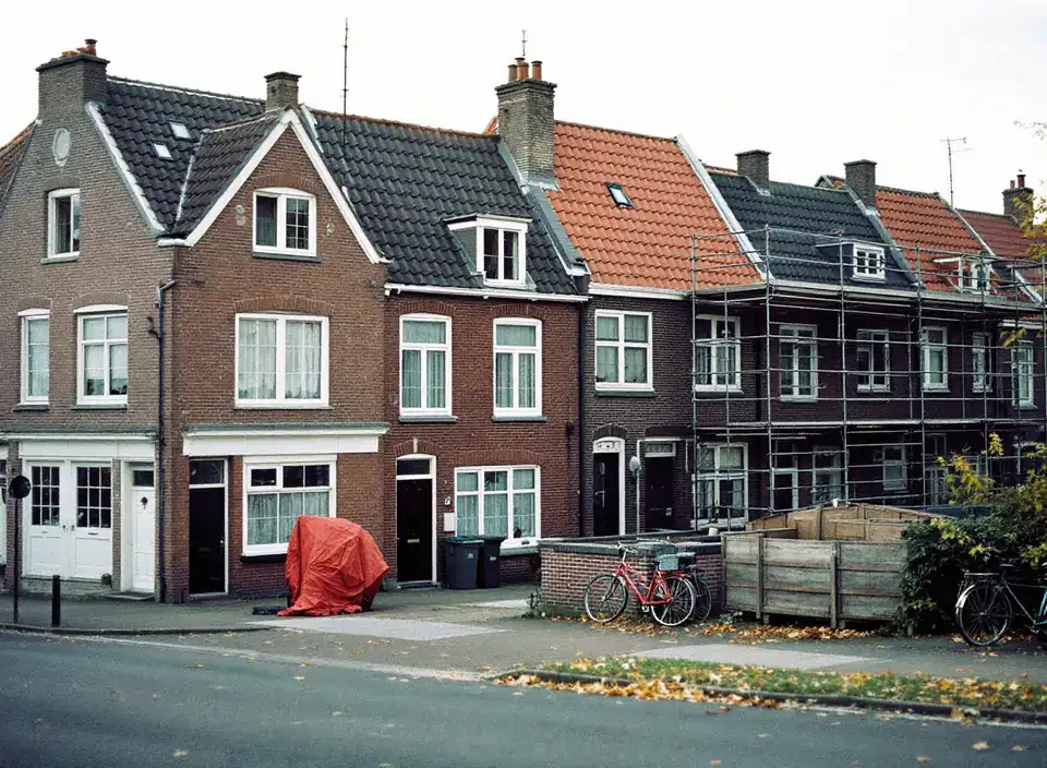 Een straat met bakstenen rijtjeshuizen uit de jaren dertig, één huis in de steigers